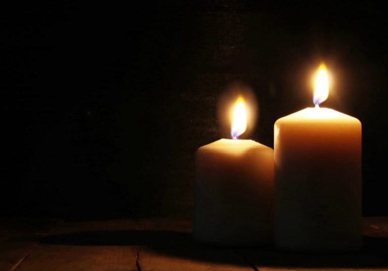 Burning candles over old wooden table with bokeh lights
